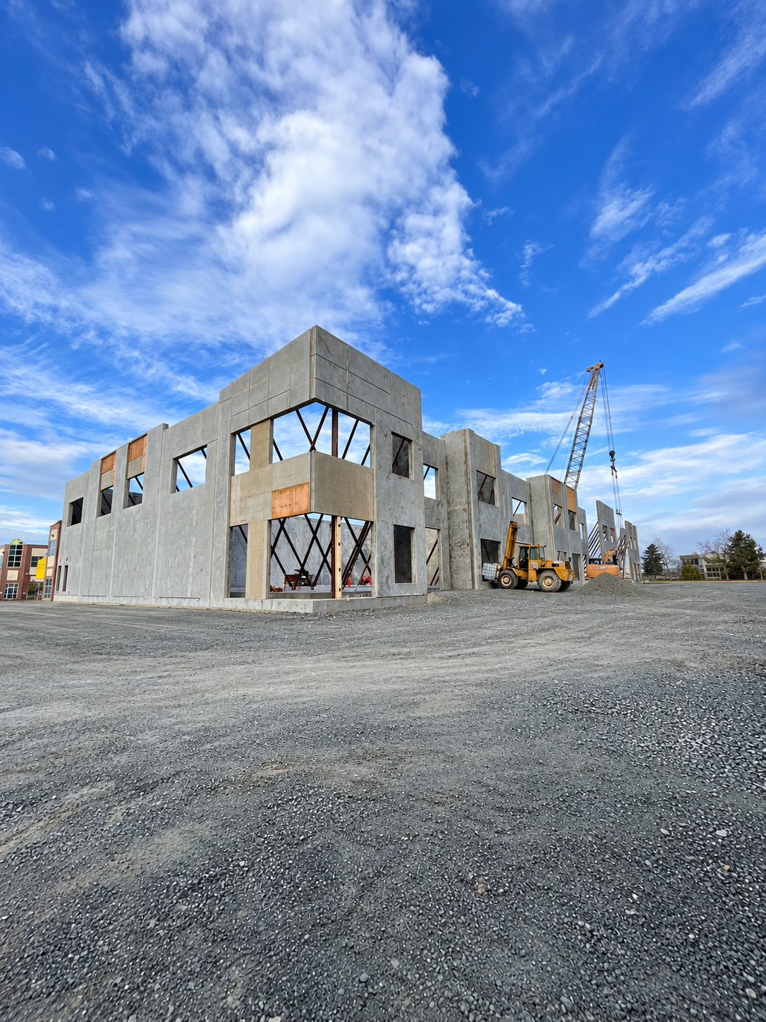 Supplied construction photograph showing tilt-up concrete panels, bracing, and site equipment